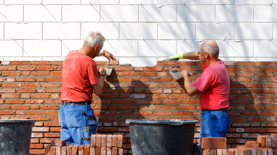 To senior murer der er i gang med at mure en væg op