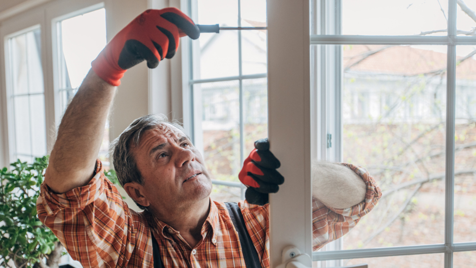 En ældre tømrer, der reparerer en dør